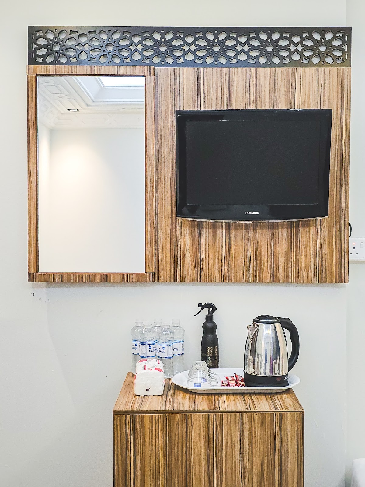 In-room amenities including a television, mirror, and a convenient beverage station with an electric kettle and bottled water, enhancing guest comfort.