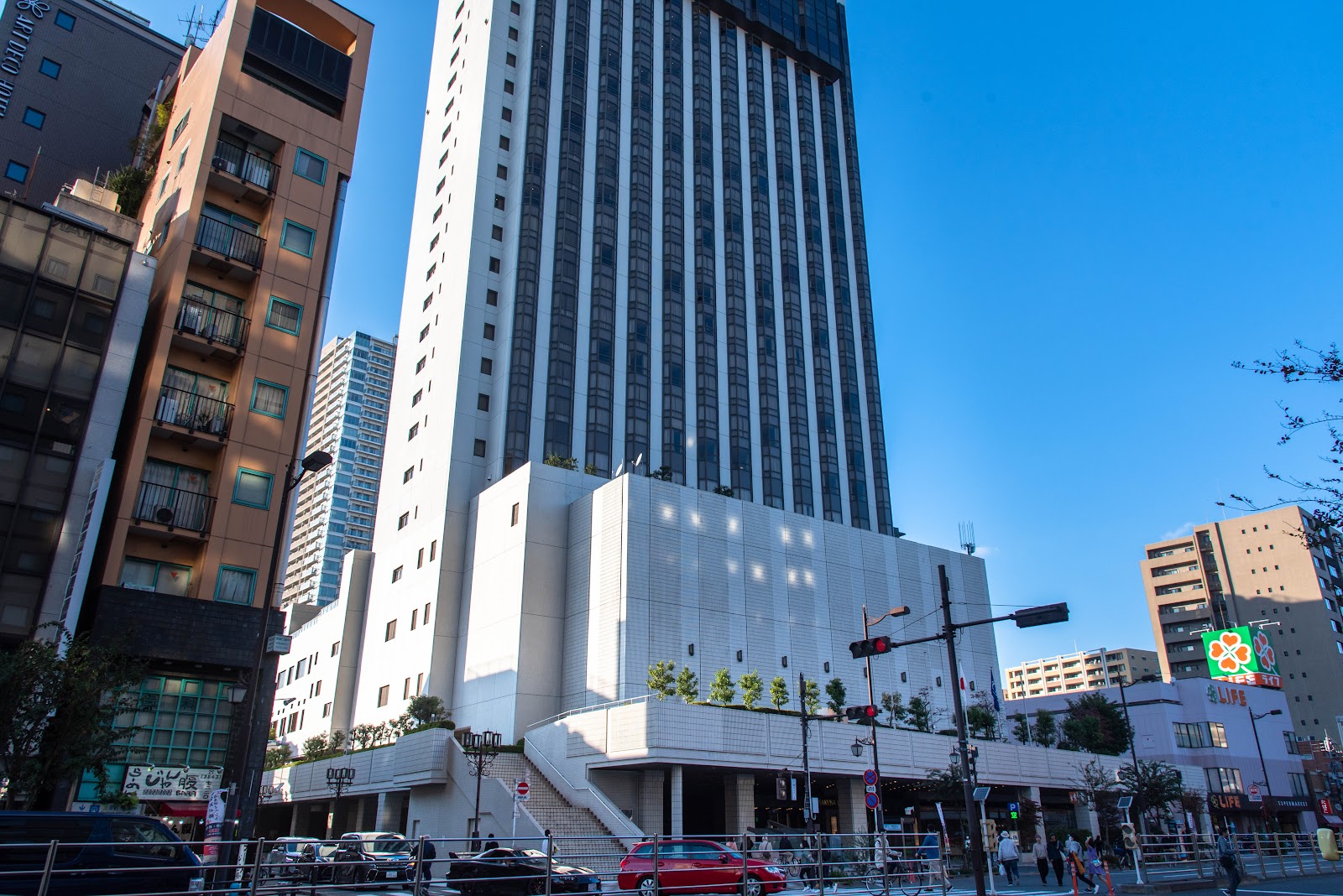 The tall, modern exterior of Asakusa View Hotel under a clear blue sky, surrounded by other urban buildings.