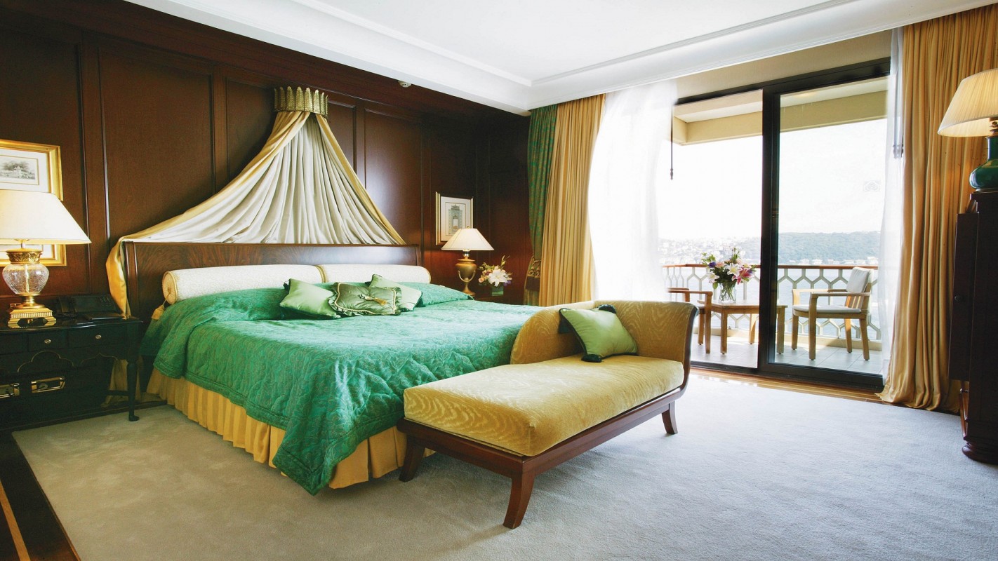 A luxurious guest room with a king-size bed, elegant traditional decor, and a private balcony overlooking the Bosphorus.
