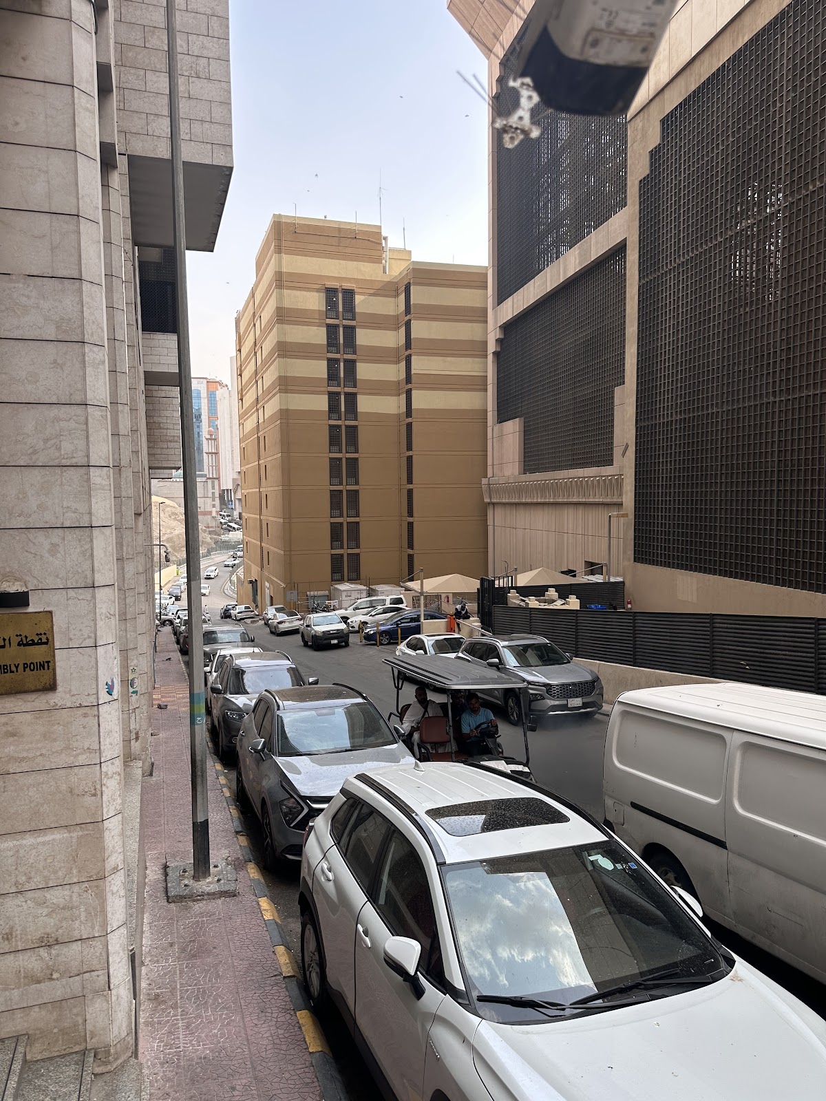 A street scene showing the immediate surroundings and approach to Elaf Ajyad Hotel, indicating its location within a busy Makkah district.