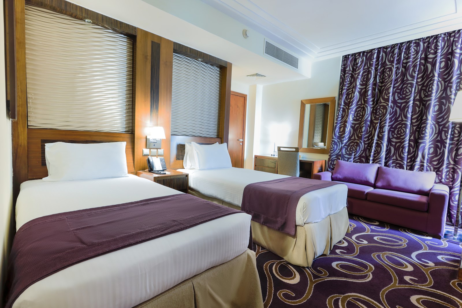 A well-arranged twin bedroom, ideal for companions or families, featuring two comfortable single beds and a sofa, offering practical personal space.