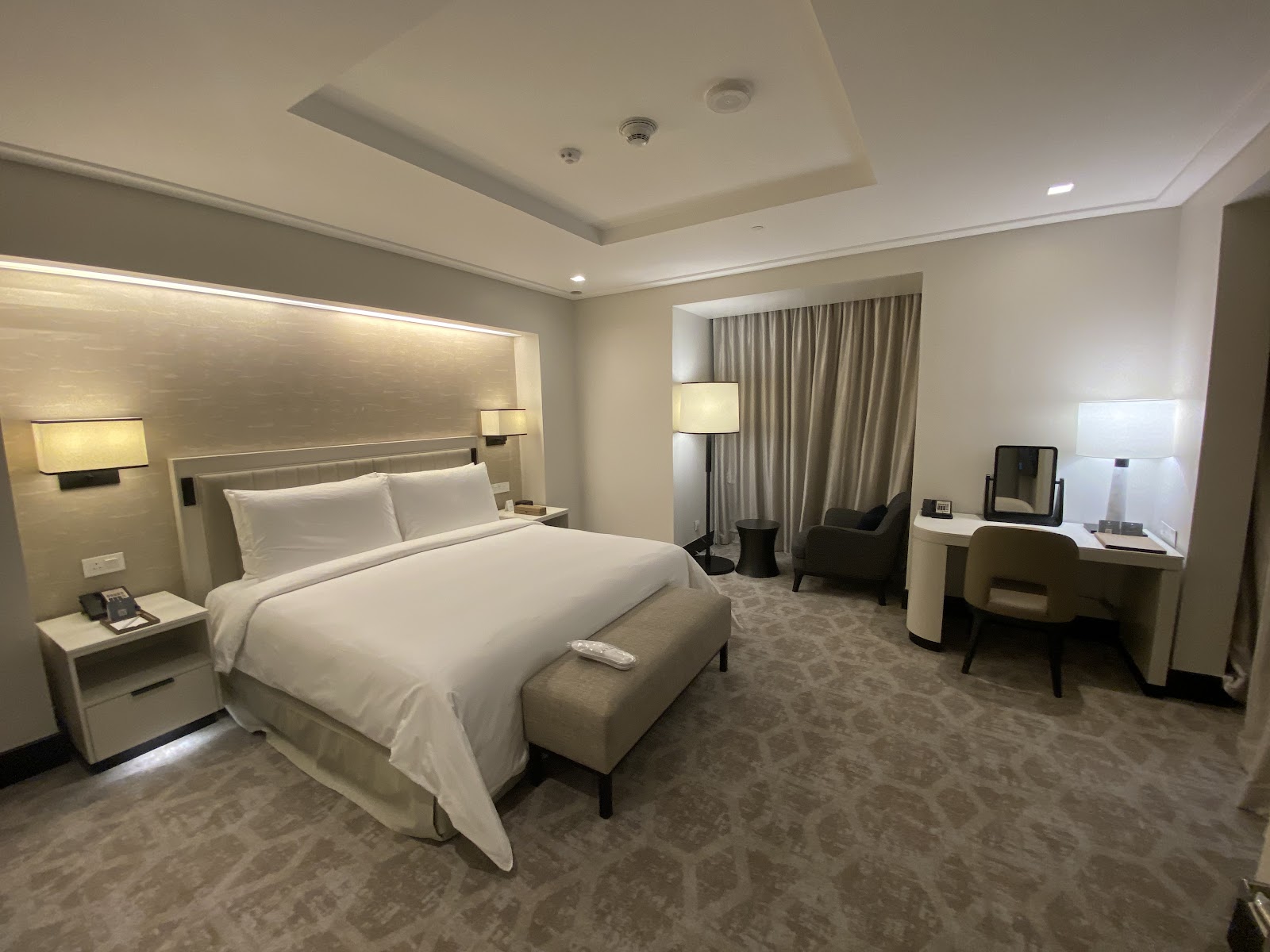 A spacious and elegantly furnished hotel room with a comfortable king-sized bed, modern amenities, and a dedicated seating/desk area, providing a high level of comfort and personal space for pilgrims to rest and rejuvenate.