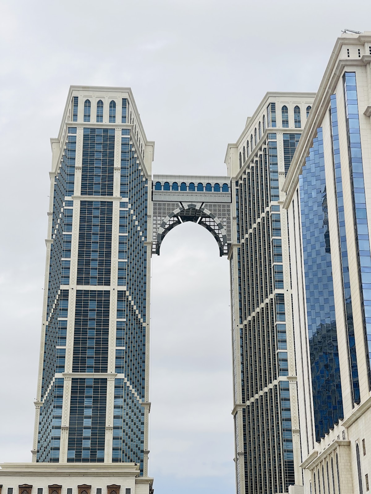A close-up view of the architectural details of Jabal Omar Hotel's twin towers, connected by a unique archway, highlighting the modern design and prominent presence within the Makkah cityscape.