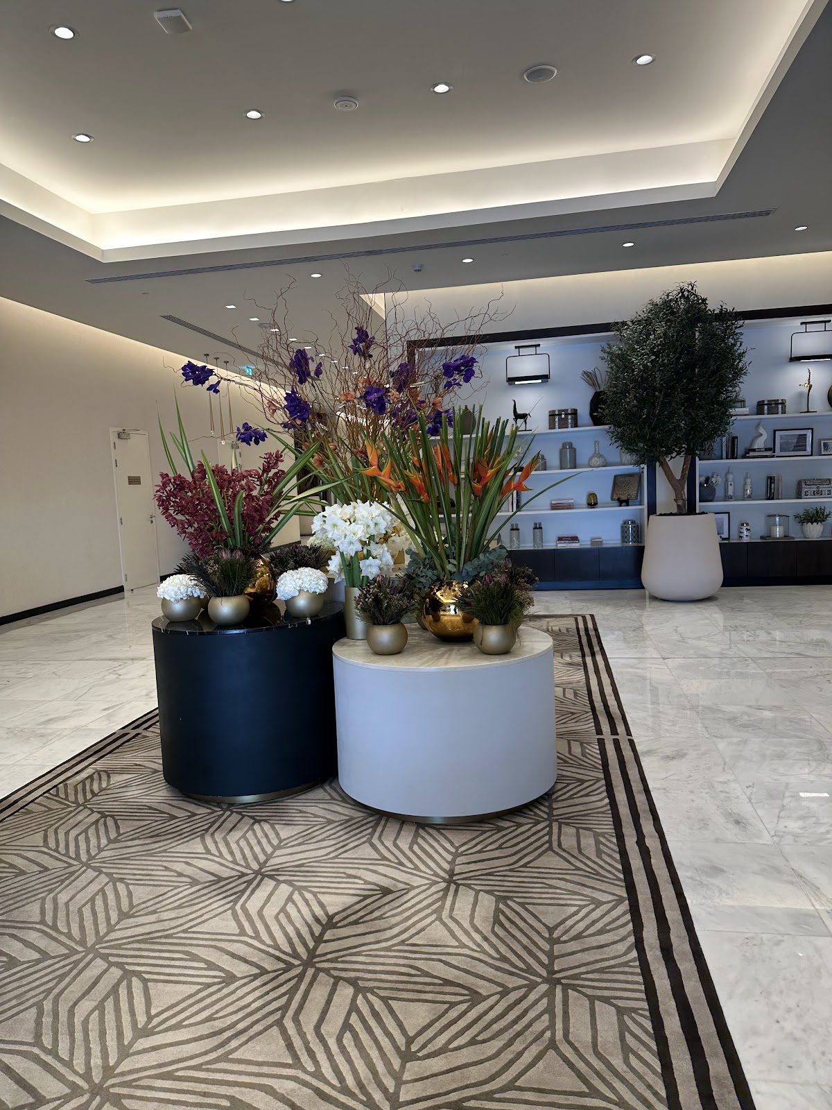 A modern and bright hotel common area or lounge, featuring contemporary design, comfortable seating, and tasteful floral arrangements, creating a serene and inviting space for pilgrims to relax or gather.
