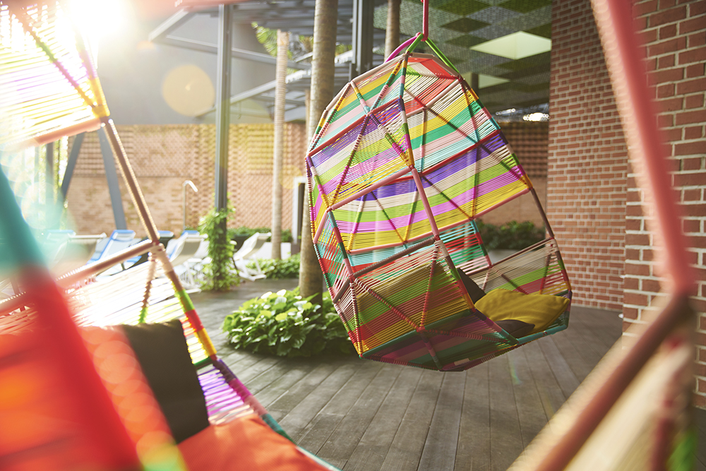 An outdoor relaxation area with colorful, unique hanging chairs and lush greenery.