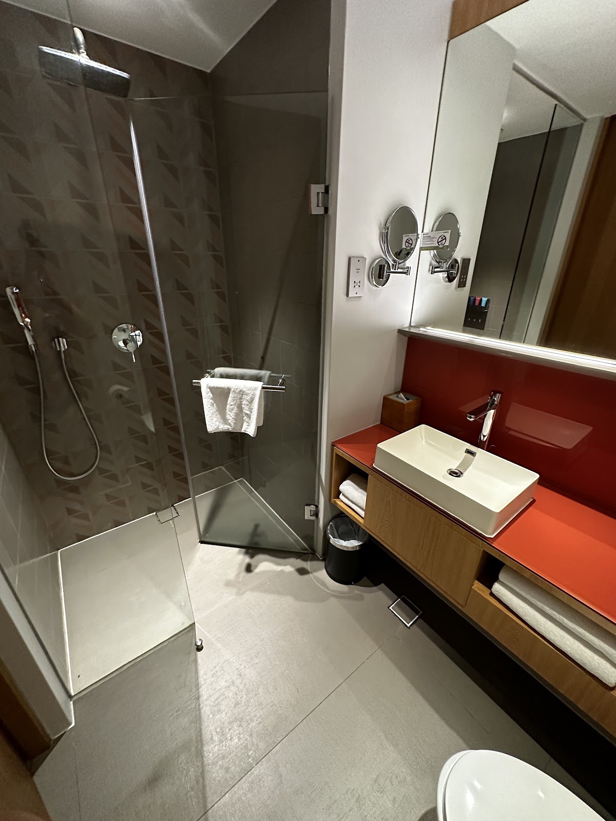 A clean, modern hotel bathroom with a walk-in shower and a stylish vanity.