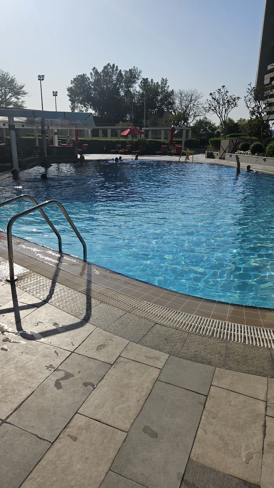 A large outdoor swimming pool with guests enjoying the water on a sunny day.