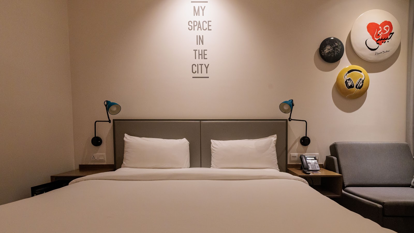 Cozy King-size bed room with modern decor and a creative wall slogan at Rove Dubai Marina.