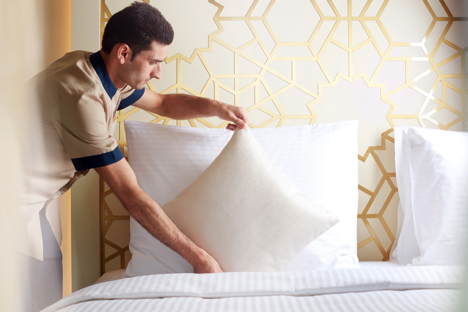 Hotel staff ensuring meticulous cleanliness and bed comfort in a guest room, reflecting high service standards.